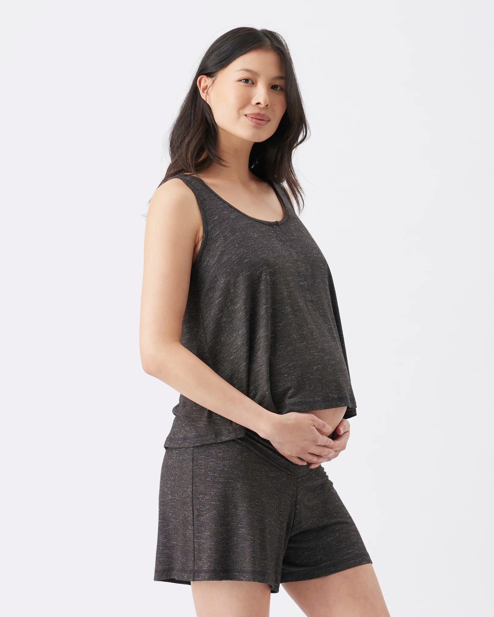 A woman modeling a dark heather gray sleeveless tank top and matching shorts against a clean white studio background.