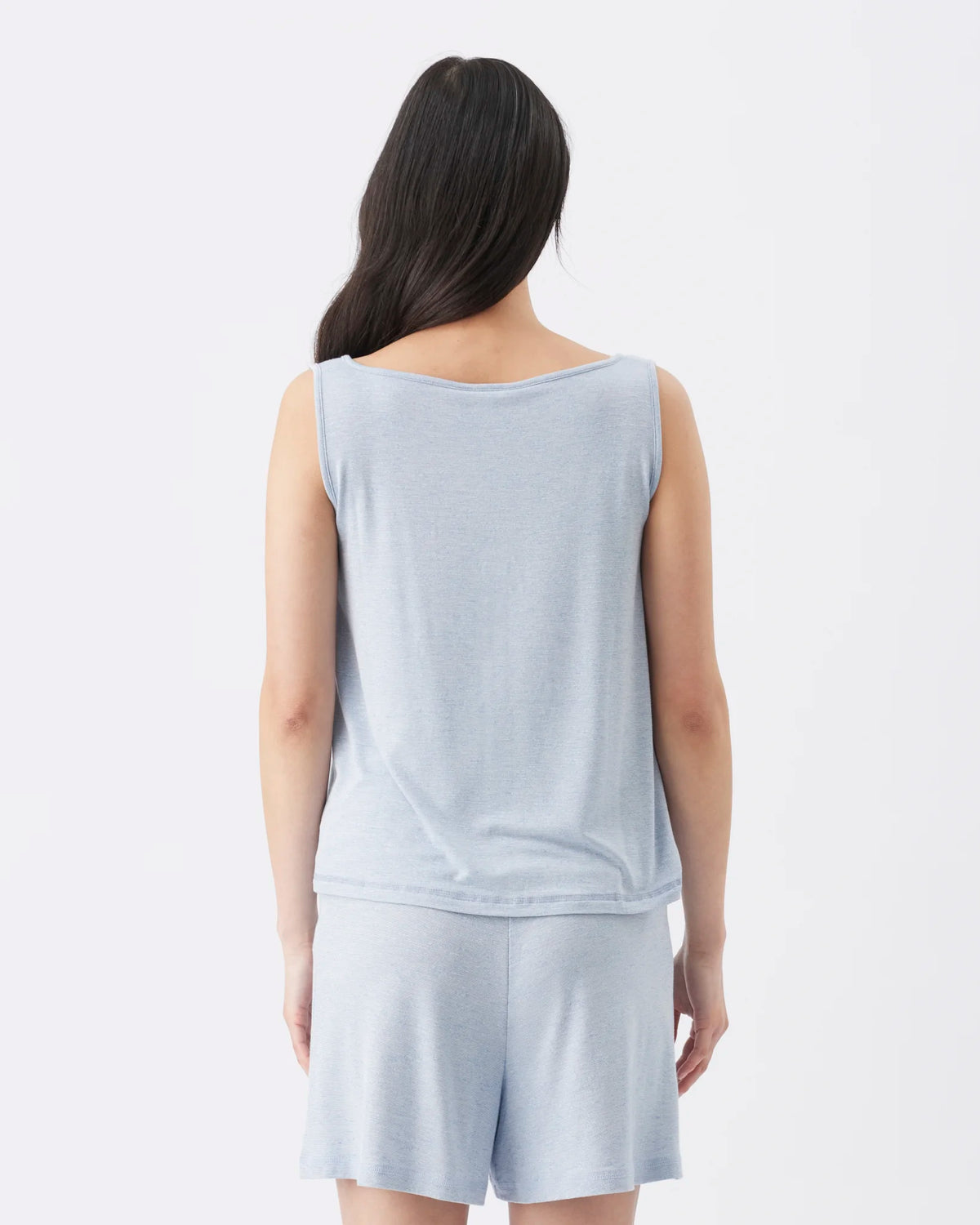 A woman shown from the back wearing a light blue sleeveless top and matching shorts against a plain white studio background.