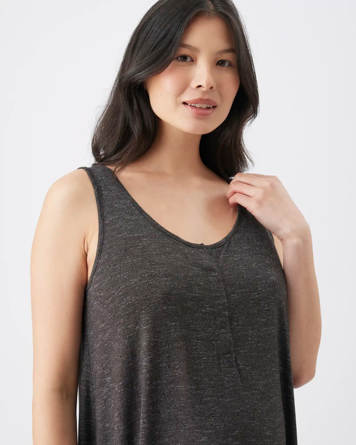 A woman wearing a dark heather gray sleeveless tank top, shown from the chest up against a plain light gray studio background.