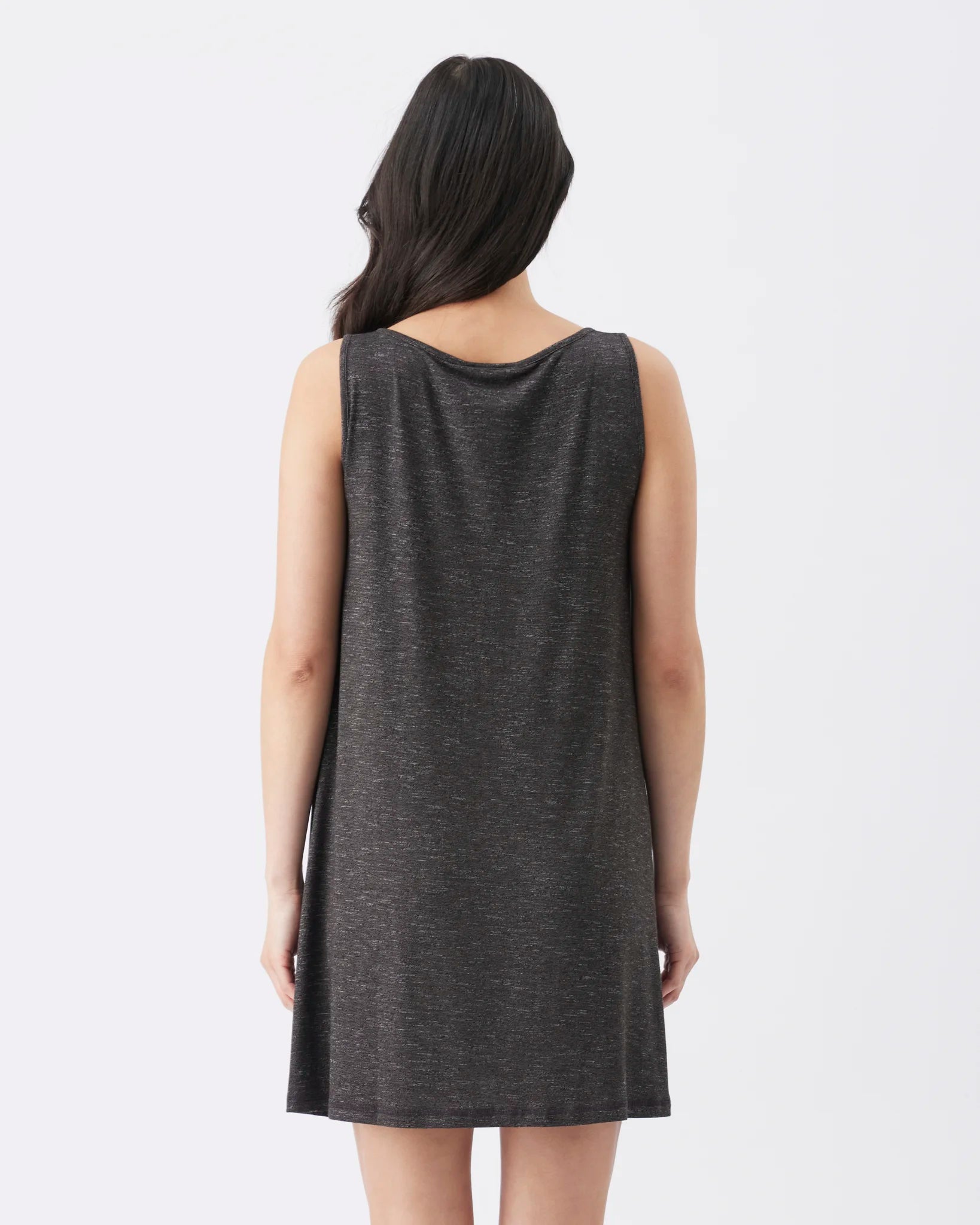 A woman viewed from the back wearing a sleeveless, knee-length dark gray heathered tunic dress against a plain white studio background.