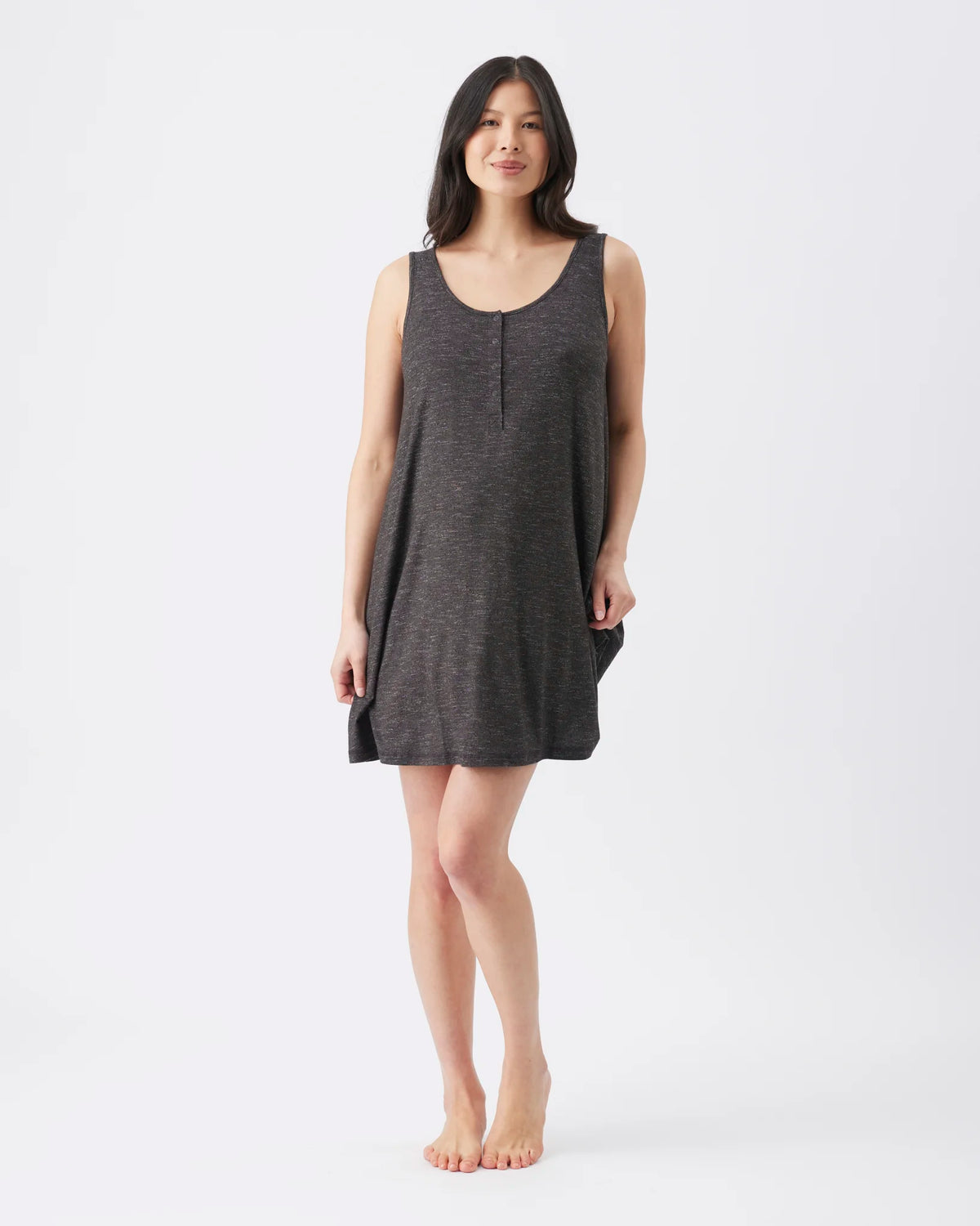 A woman modeling a dark gray sleeveless knit nightshirt or tunic dress with a scoop neckline and a small center front slit, standing against a plain white studio background.