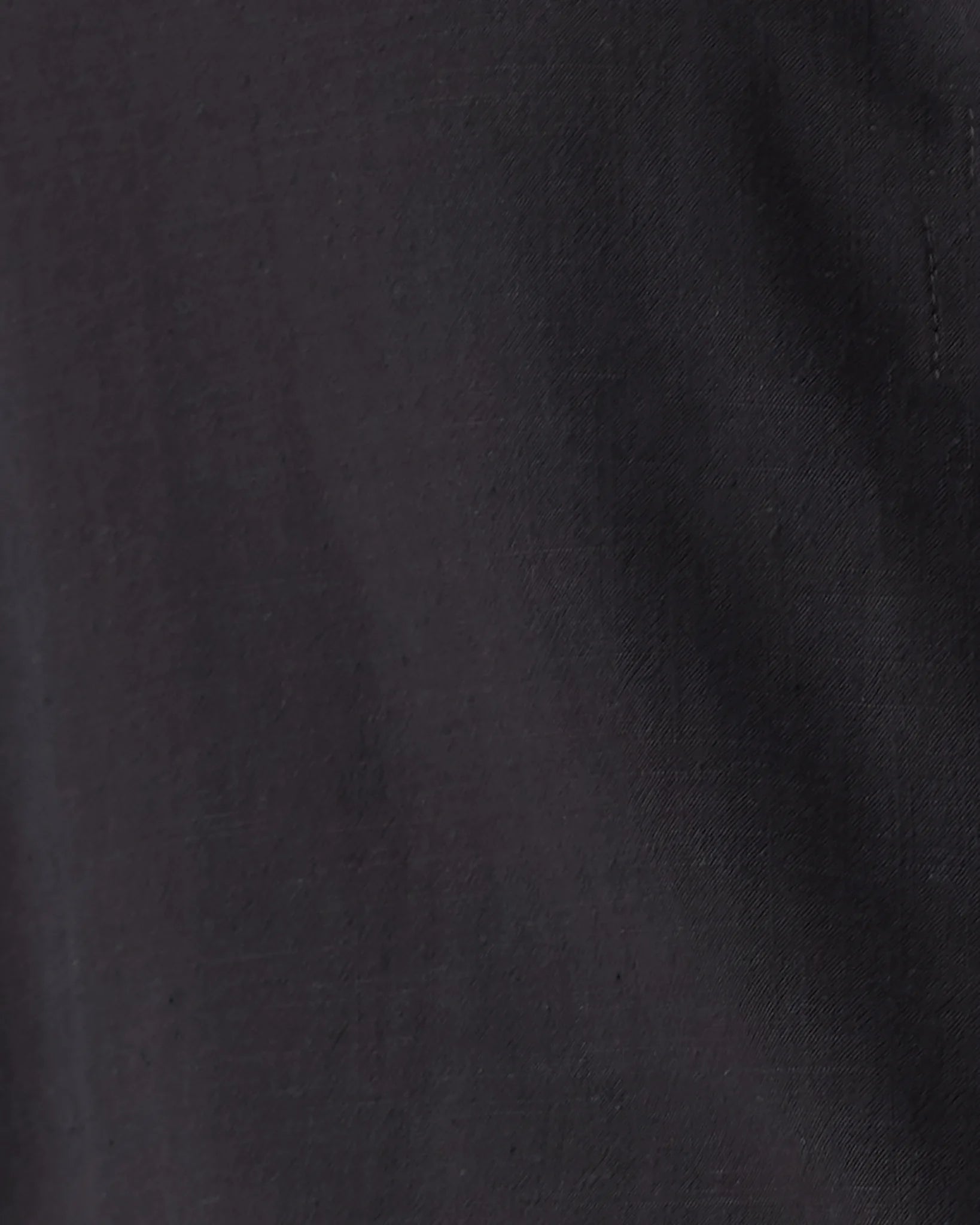A close-up of a dark charcoal gray or black textured fabric, showing the weave and subtle folds.