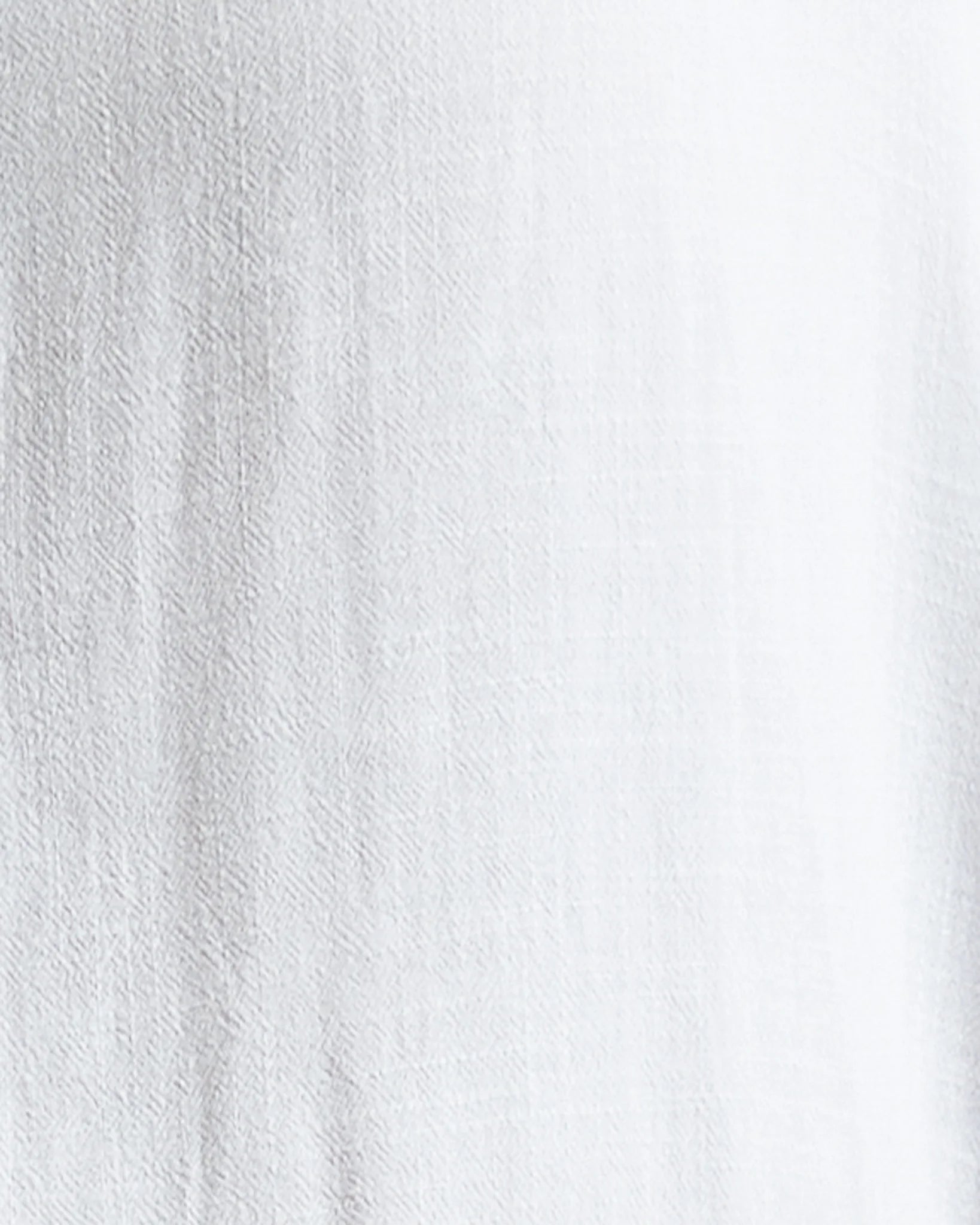A close-up of a white textured fabric surface with soft vertical folds and a slightly sheer, lightweight appearance.
