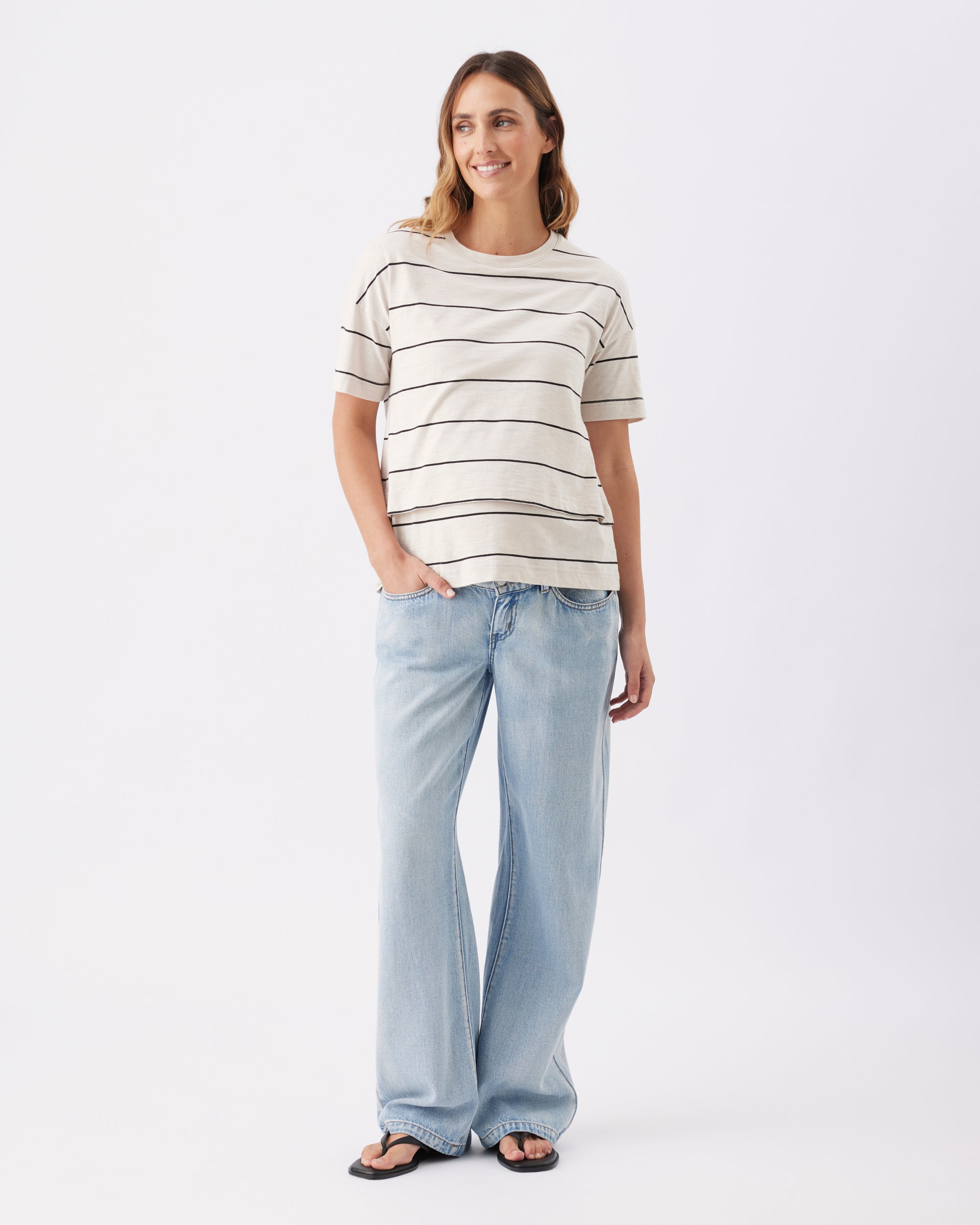 Woman wearing a striped shirt and light blue jeans on a white background