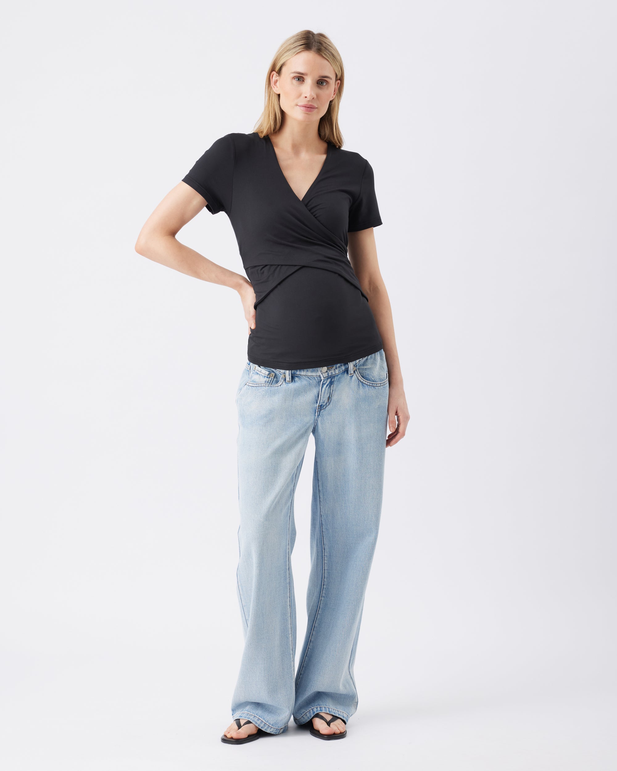 Full length view of a woman wearing a black top and light blue jeans on a white background