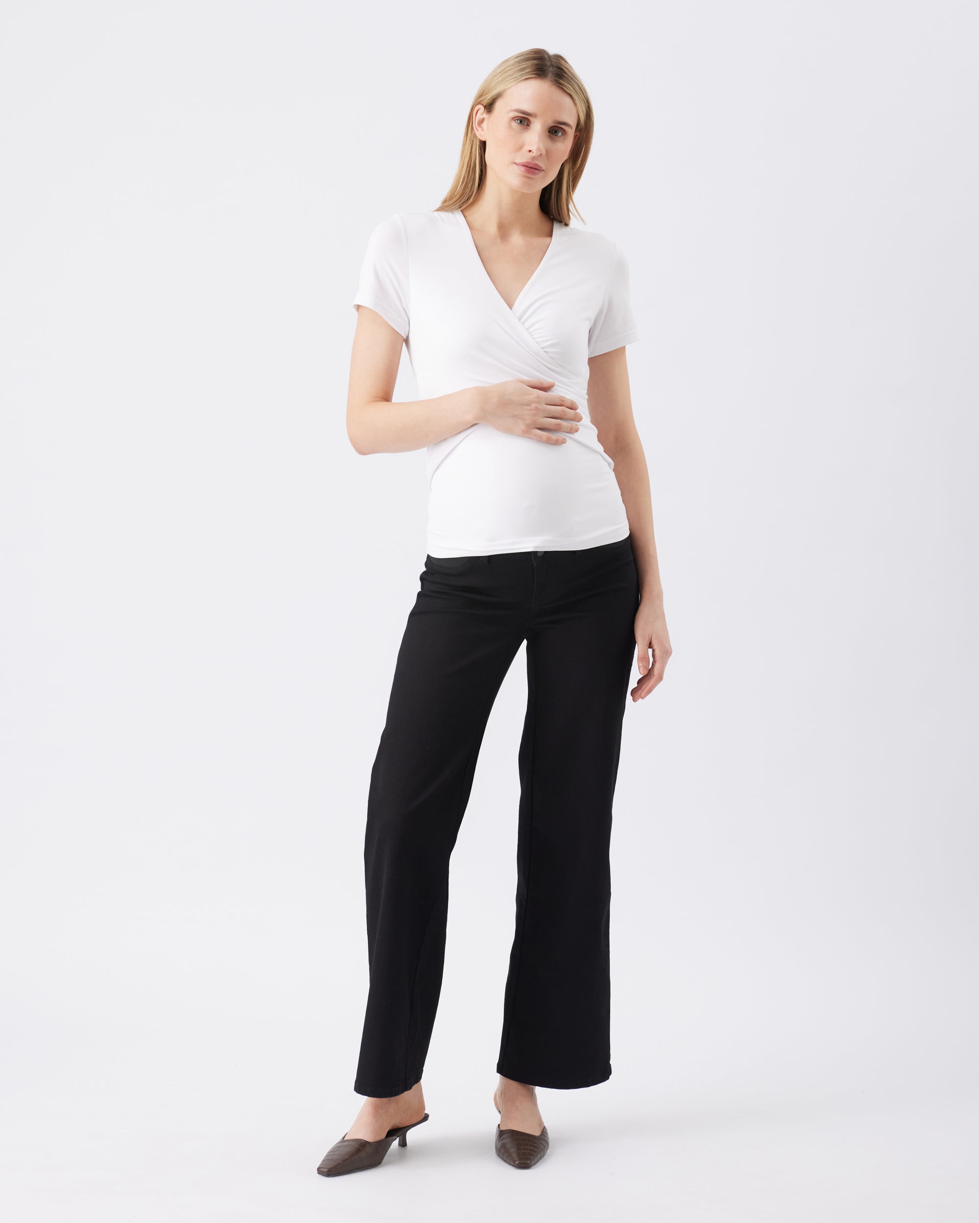 Full length image of a woman wearing a white top and black pants on a white background