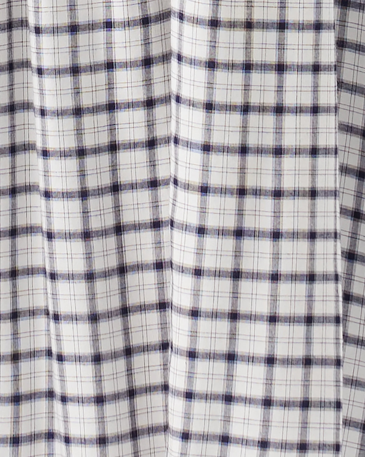 A close-up of a white fabric with a navy blue and thin gray plaid pattern, showing soft vertical folds.