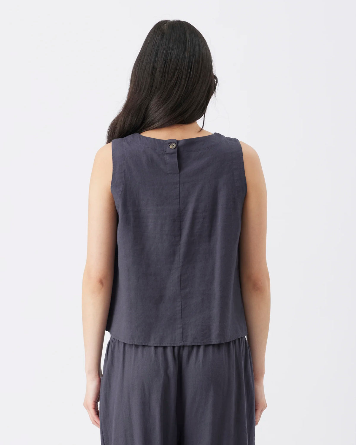 A woman shown from the back wearing a sleeveless dark gray top and matching skirt against a plain white background.