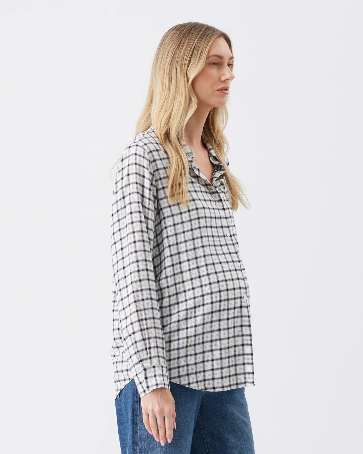 A woman wearing a black and white checkered long-sleeve button-up shirt and blue jeans, shown from a side profile against a plain white studio background.