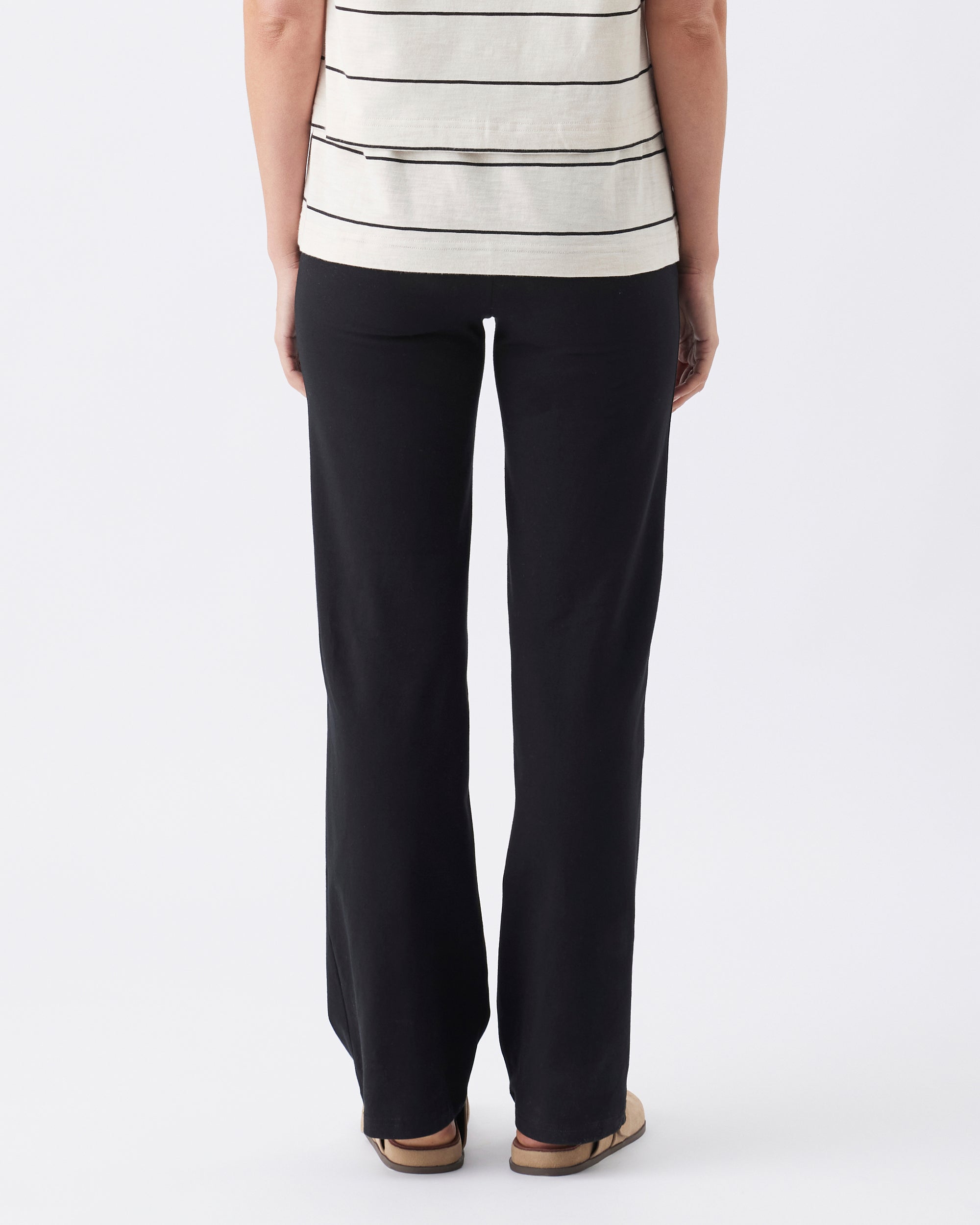 Back view of a person wearing a striped top and black pants on a white background