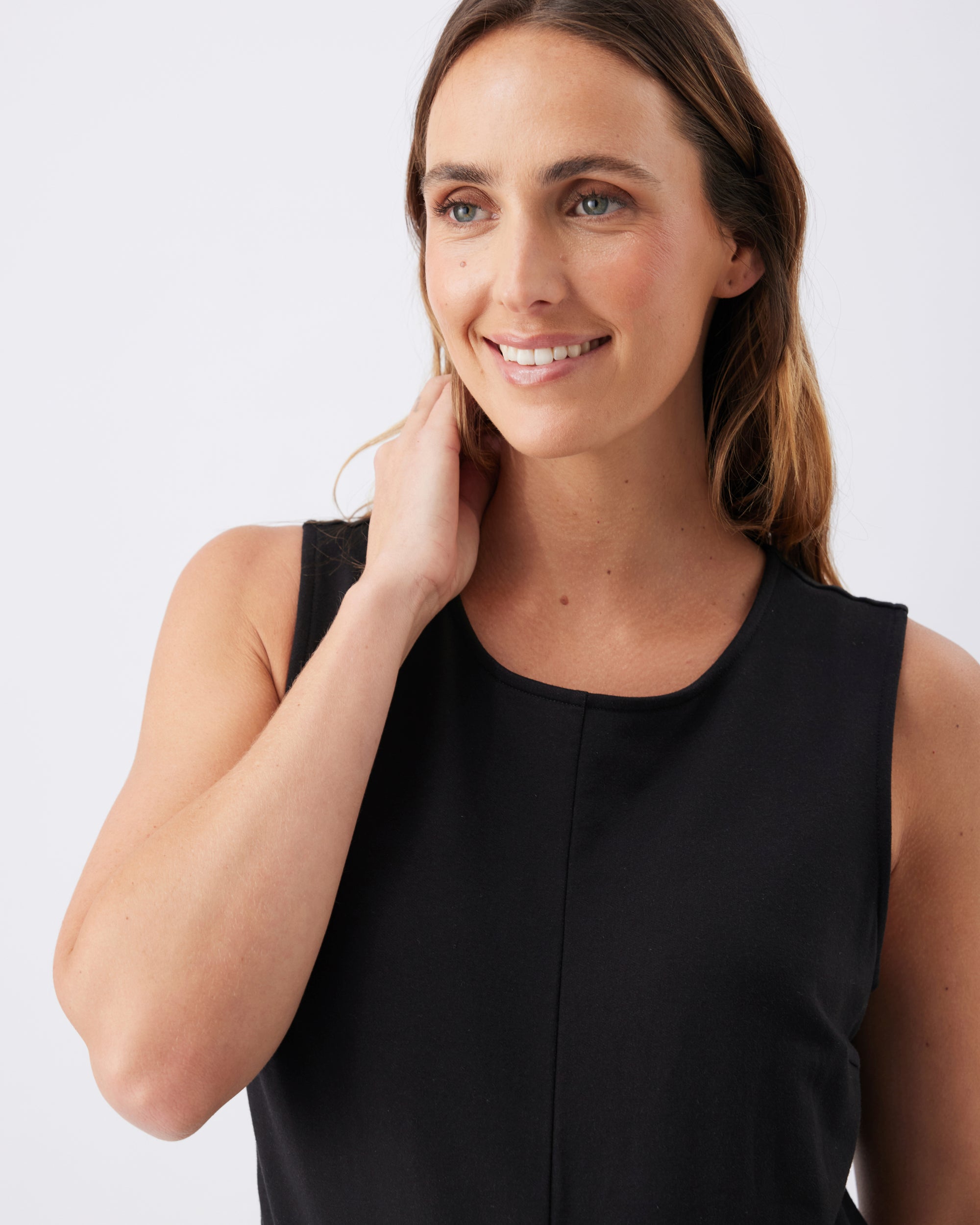 Closeup of a woman wearing a black sleeveless jumpsuit with a round neckline.