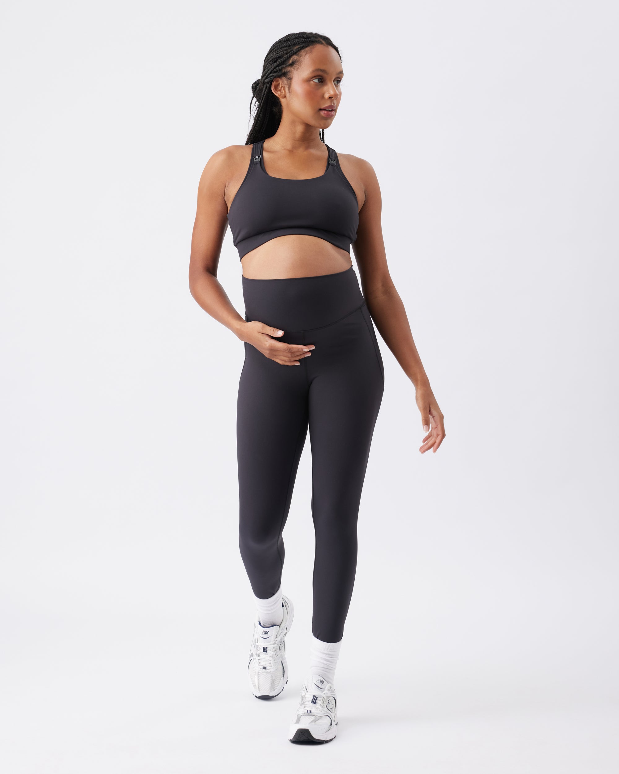 Pregnant woman wearing a black athletic outfit on a white background
