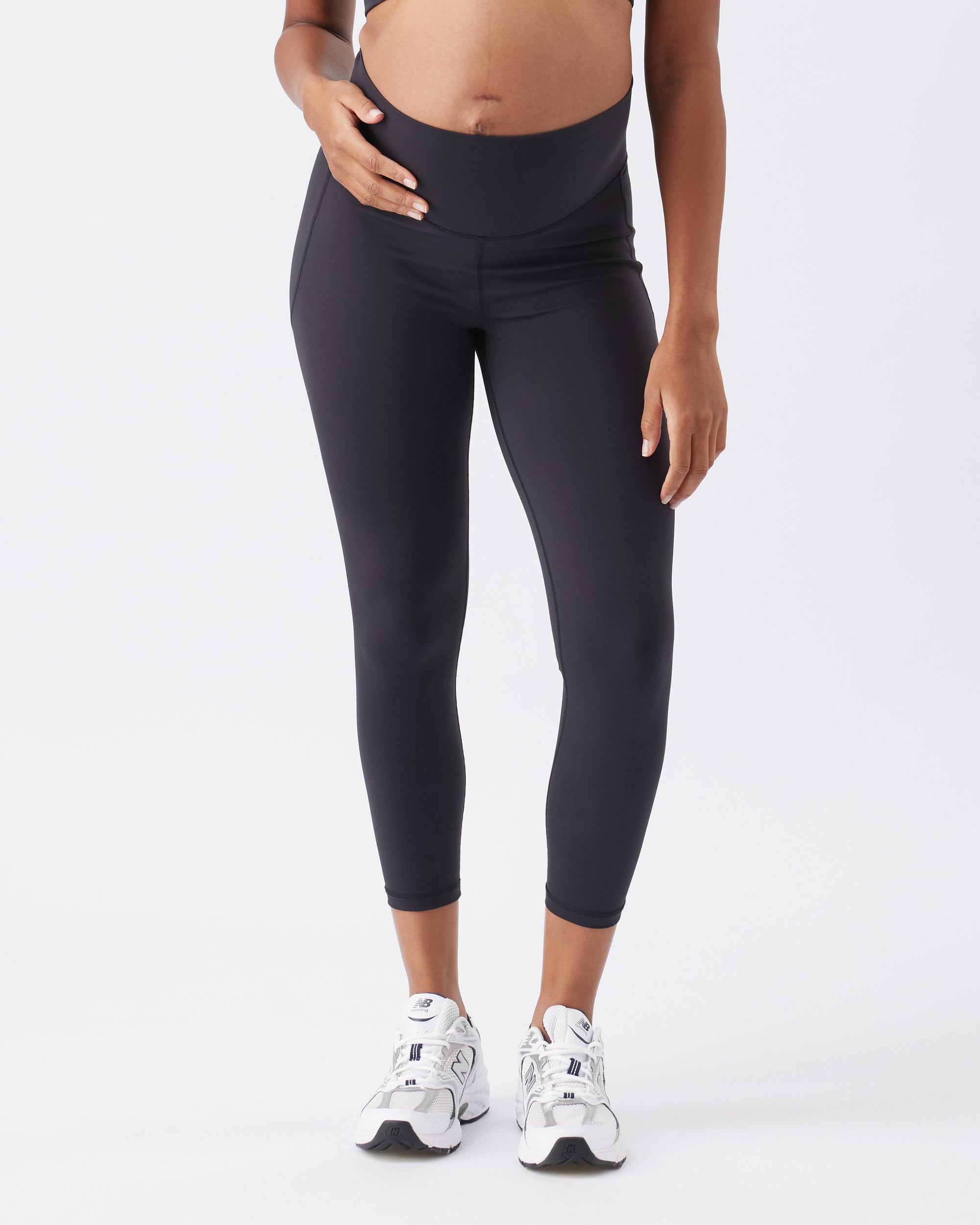 Woman wearing black leggings and white sneakers on a white background