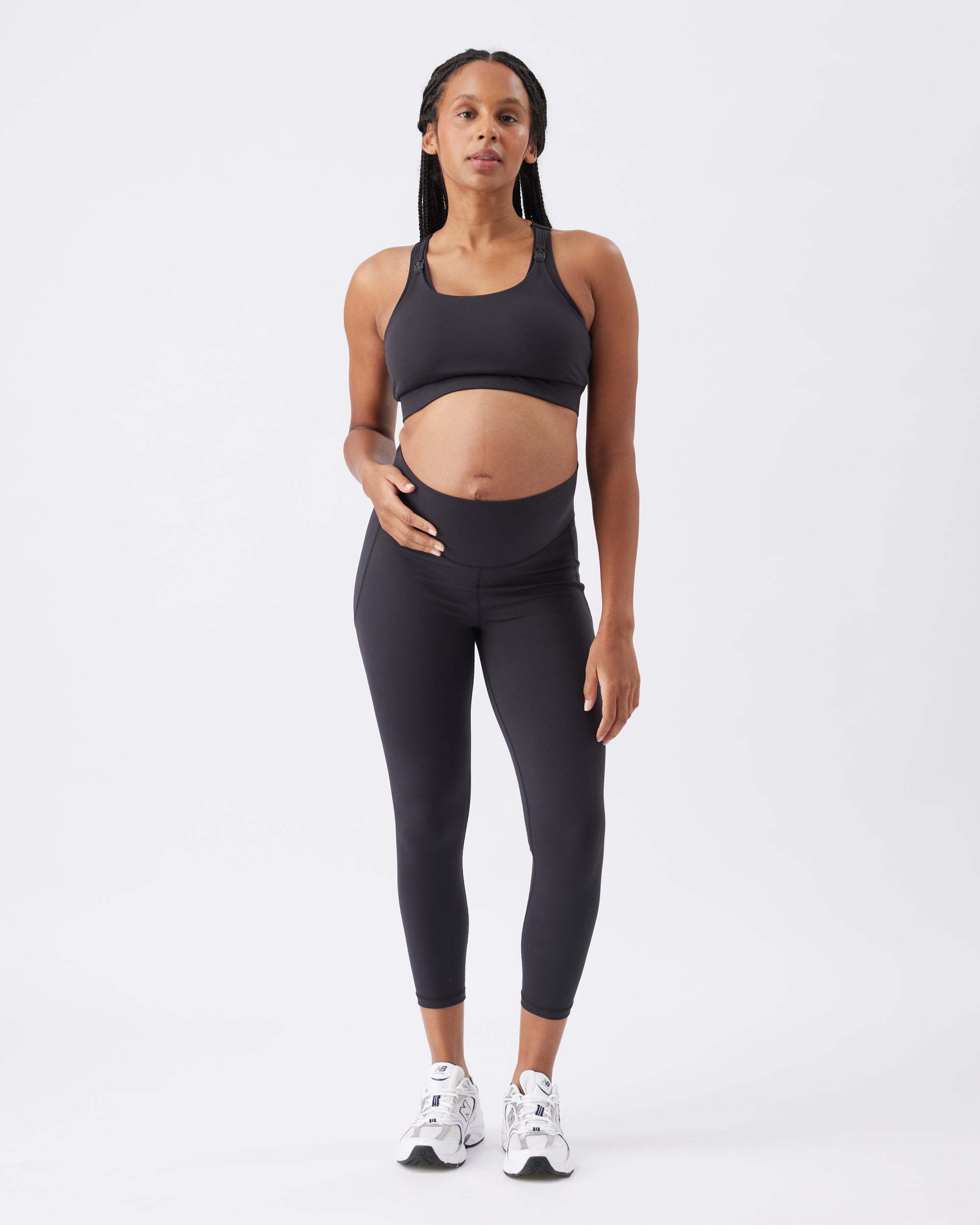 Pregnant woman wearing a black athletic outfit on a white background