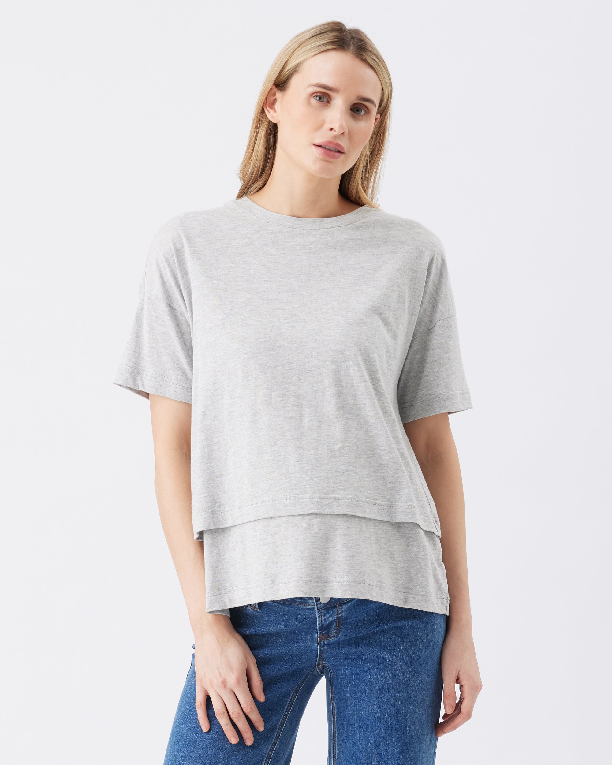 Woman wearing a gray t-shirt and blue jeans on a white background