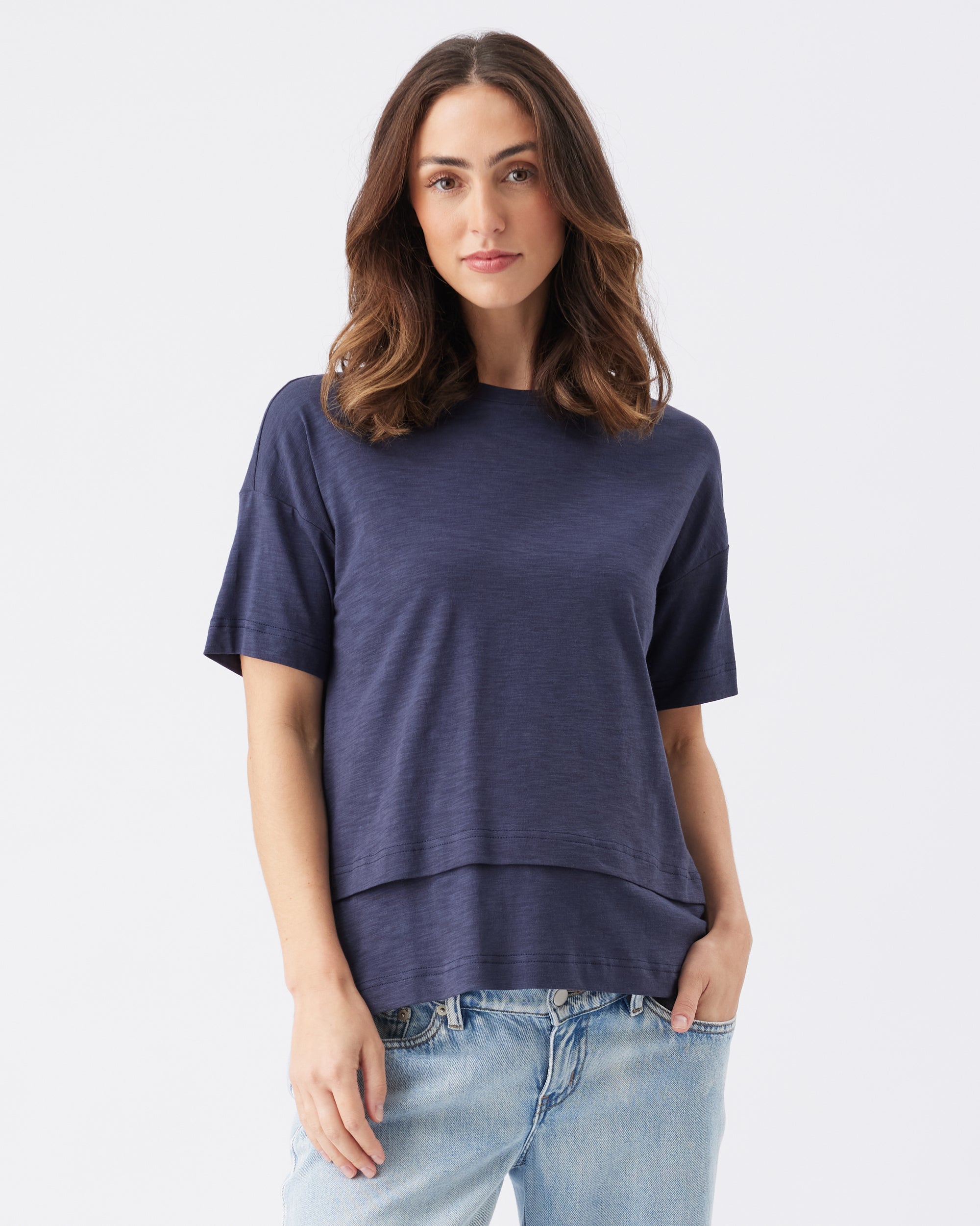 Woman wearing a navy blue t-shirt and light blue jeans on a white background
