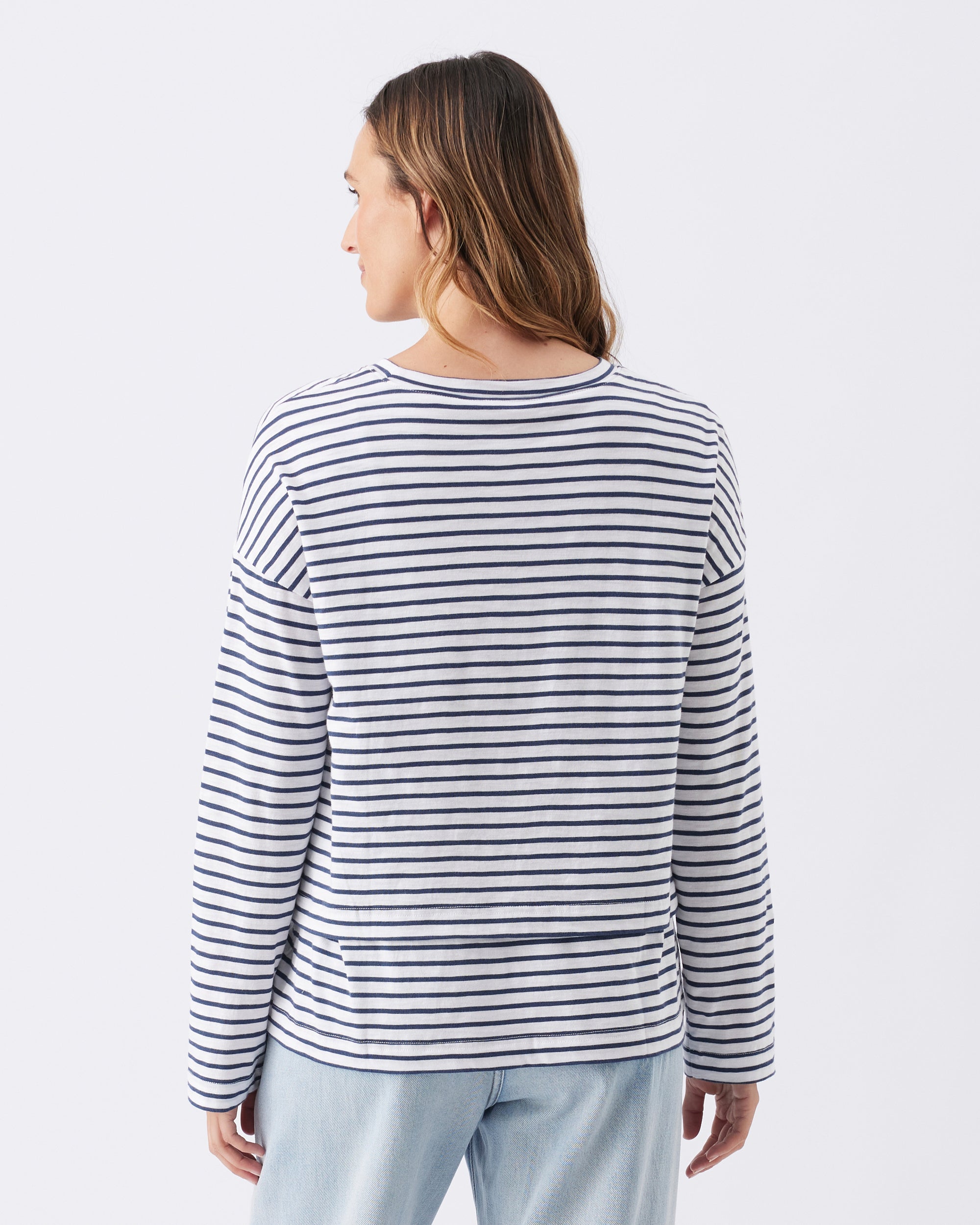 Back view of a woman wearing a striped long-sleeve shirt on a white background
