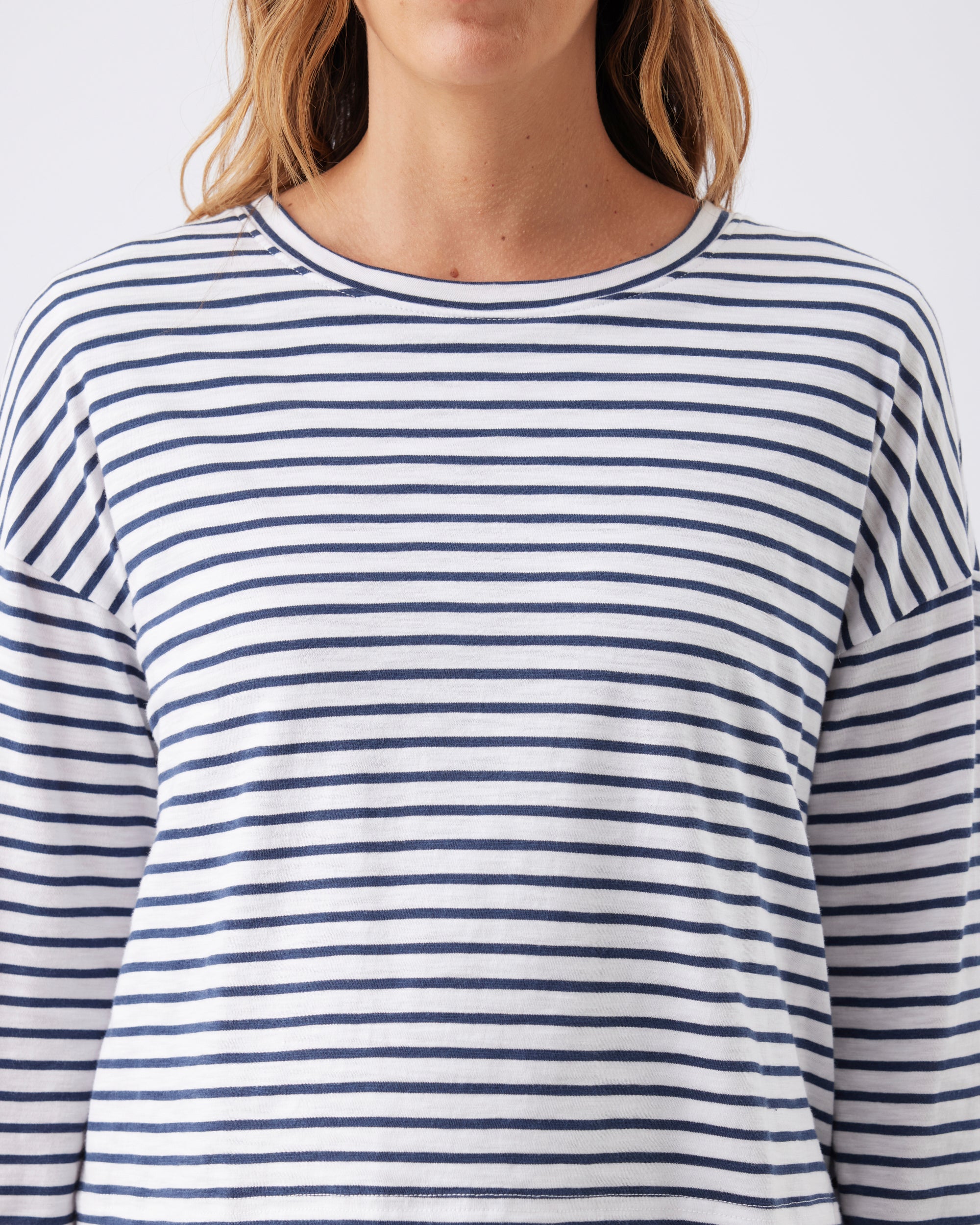 Closeup view of a woman wearing a blue and white striped long-sleeve shirt against a light background