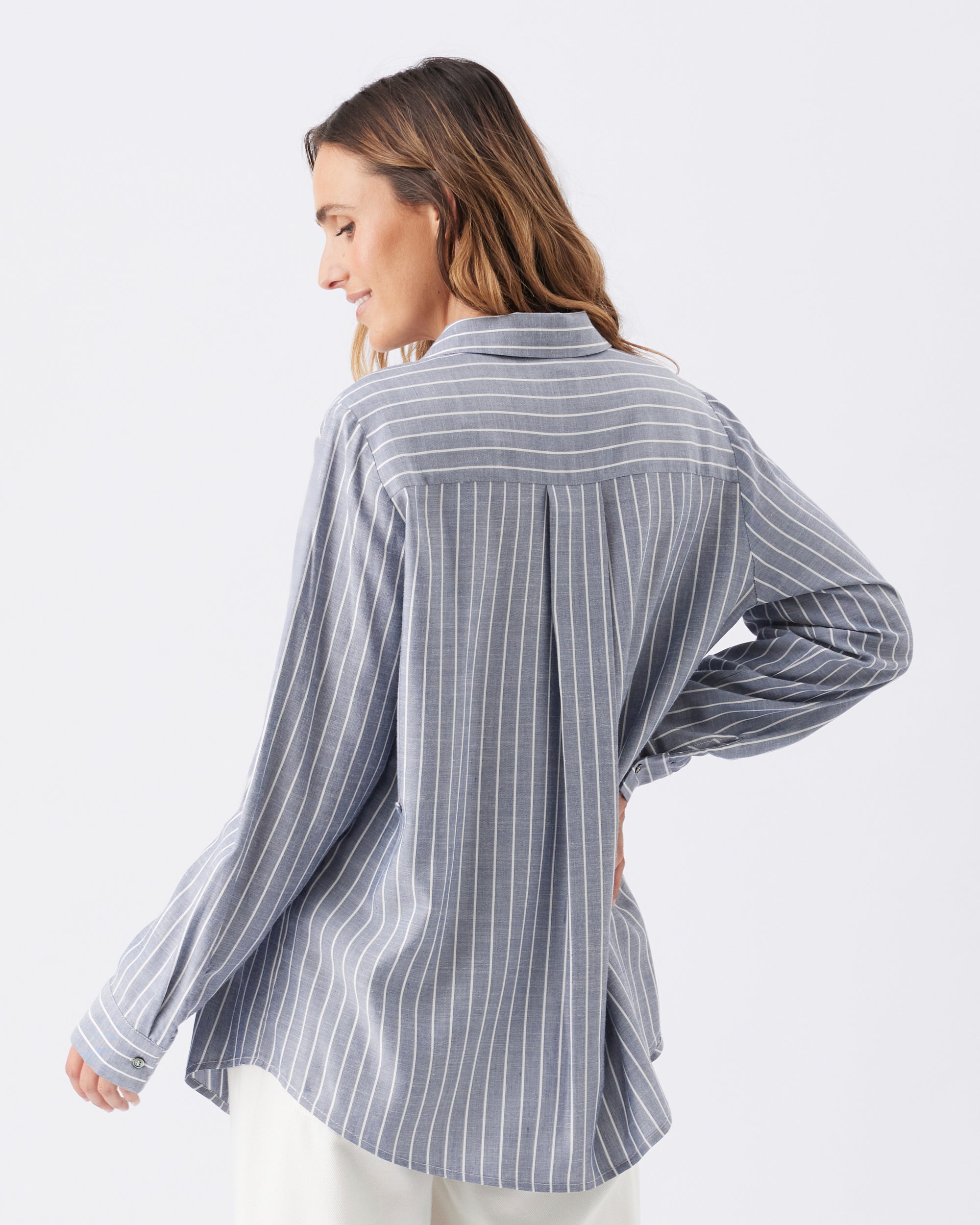 Back view of a woman wearing a blue and white striped shirt on a white background